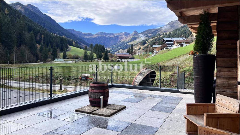 Große geflieste Terrasse mit Sitzgelegenheiten und atemberaubendem Blick auf die Berge.