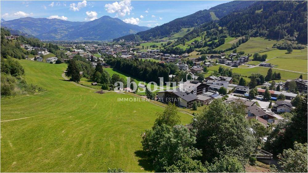 Panoramablick über ein Tal mit einer Ortschaft, umgeben von grünen Hügeln und majestätischen Bergen