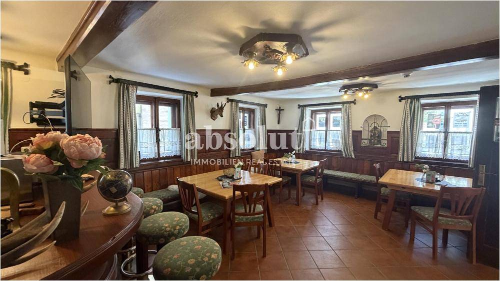 Traditioneller Speisesaal mit Holztischen, Bänken und rustikalen Wandverkleidungen.