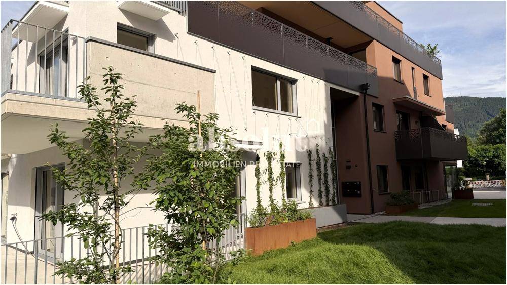 Moderne Wohnanlage mit weißer und brauner Fassade, Balkonen und grüner Umgebung.