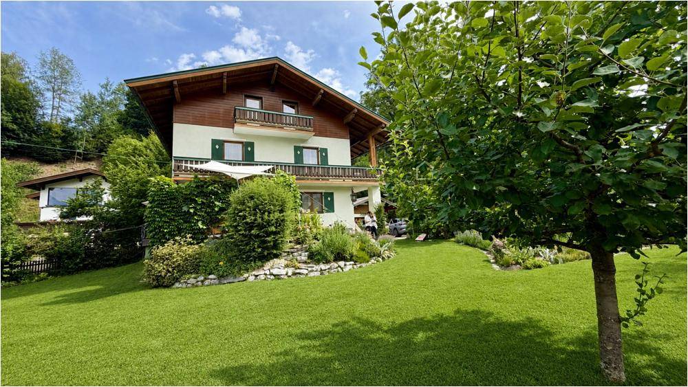 Großzügiger Gartenbereich mit Rasenfläche und dem charmanten Wohnhaus am Hang.