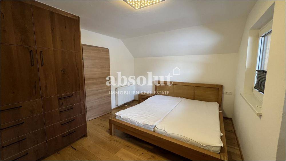 Schlafzimmer mit großem Holzkleiderschrank, Doppelbett und Holzboden.