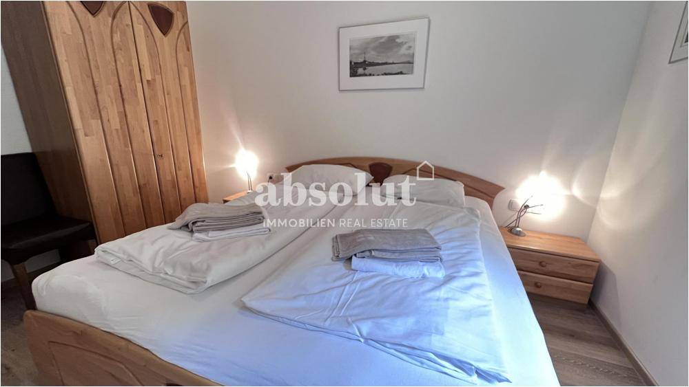 Schlafzimmer mit Doppelbett, Holzmöbeln und Dachschräge, bietet eine gemütliche Atmosphäre.