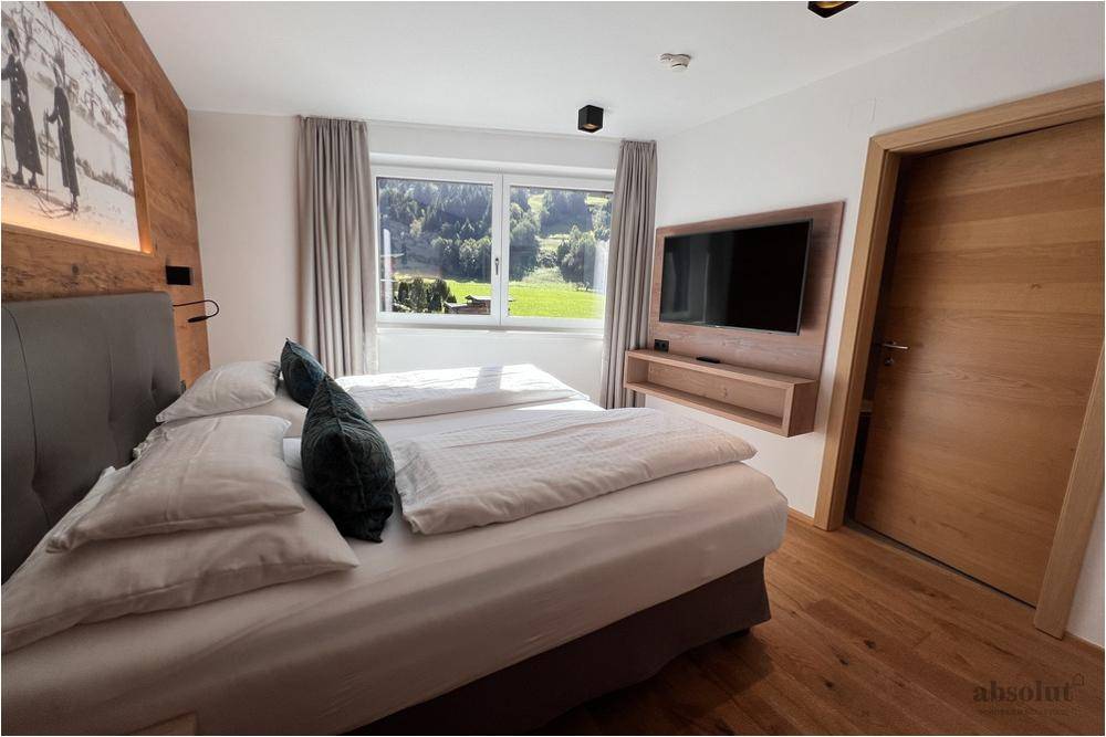 Gemütliches Schlafzimmer mit Doppelbett, Holzboden und weitem Blick ins Grüne.