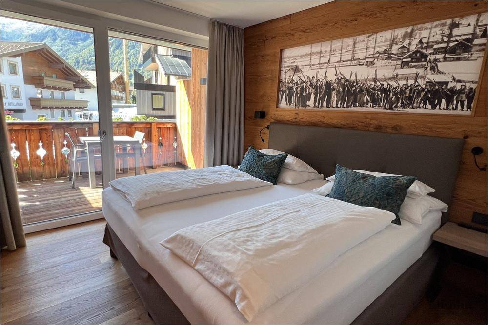 Helles Schlafzimmer mit Balkonzugang, Doppelbett und traditioneller Wanddekoration.