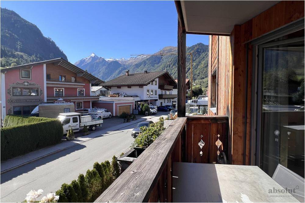 Blick vom Balkon auf die umliegende Berglandschaft und die Dorfstraße.