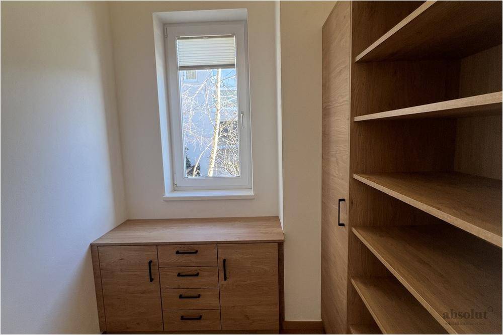 Kleiner Raum mit Holzschränken, Regalen und einem Fenster, ideal als Abstellraum oder Ankleide.