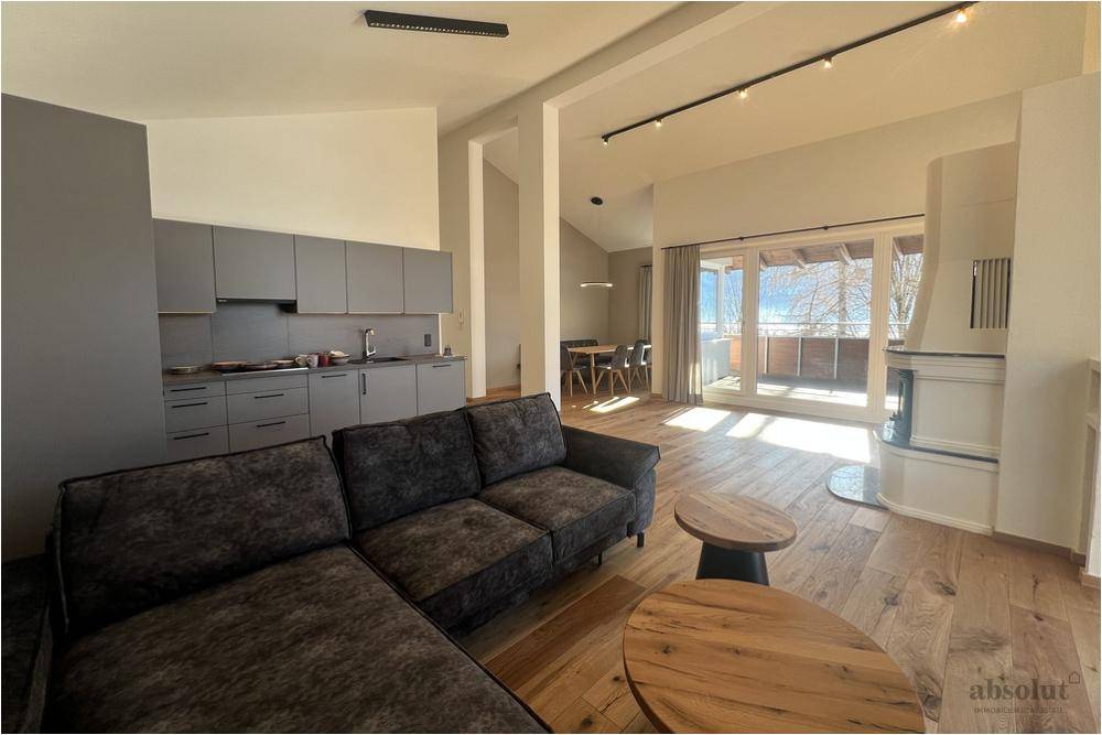 Offener Wohnbereich mit moderner grauer Küche, Essbereich und Zugang zur Terrasse mit Bergblick.