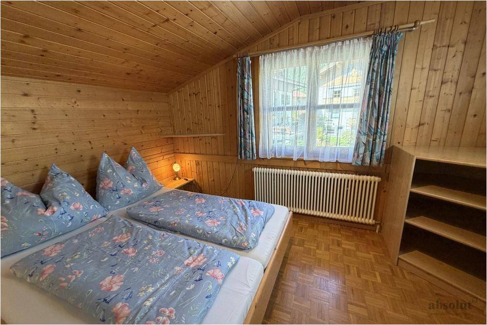 Gemütliches Schlafzimmer im Dachgeschoss mit Holzverkleidung, Doppelbett und Fensterblick.
