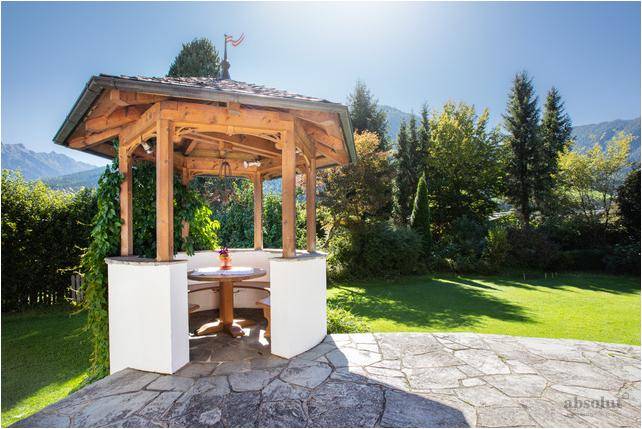 Idyllischer Pavillon im Garten mit Sitzgelegenheiten und weitem Blick auf die Berge.