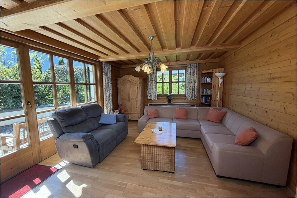 Geräumiges Wohnzimmer mit Holzwänden, Holzbalkendecke und großer Eckcouch für gemütliche Abende.