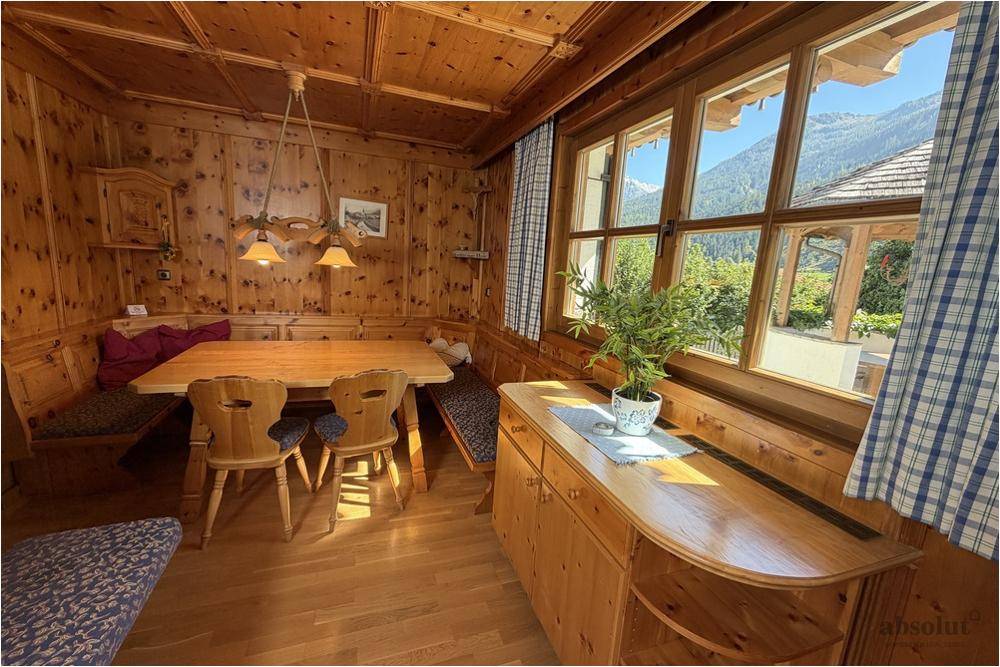 Traditioneller Essbereich mit Holztäfelung, Eckbank und Blick auf die umliegende Berglandschaft.