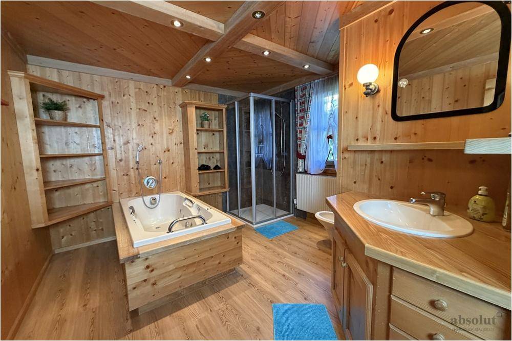 Geräumiges Badezimmer mit Holzmöbeln, Whirlpool und Duschkabine für entspannende Momente.