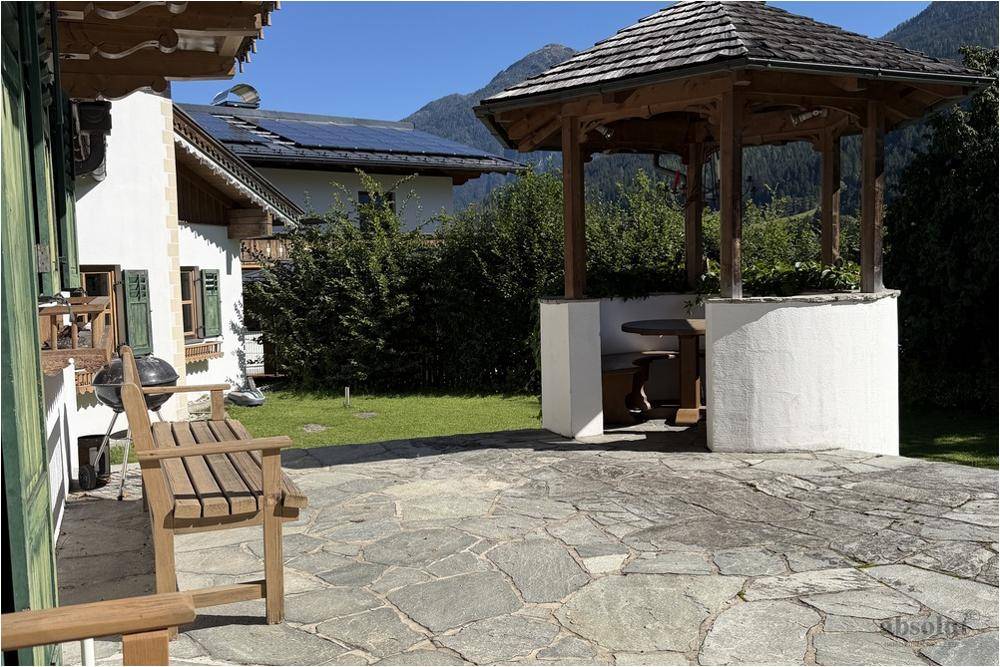 Große Steinterrasse mit Gartenmöbeln, Grillplatz und Pavillon im Grünen.