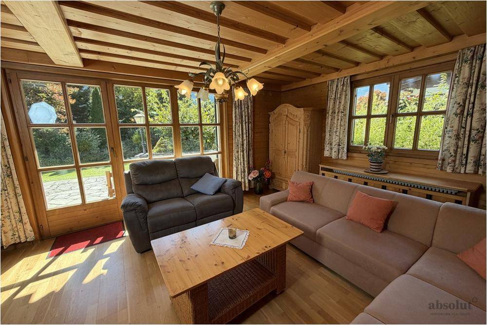 Rustikales Wohnzimmer mit Holzbalkendecke, bequemen Sofas und Zugang zum Garten.