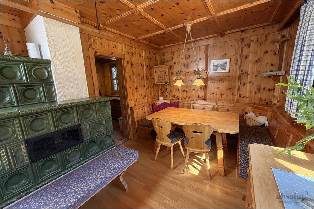 Gemütlicher Essbereich mit Kachelofen, Holztisch und Eckbank, ideal für gesellige Runden.