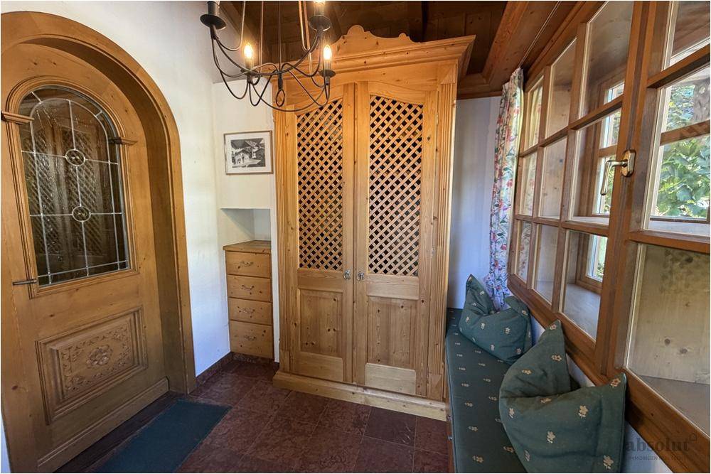 Gemütlicher Eingangsbereich mit Holztür, Einbauschrank und Sitzbank am Fenster im alpenländischen Stil.