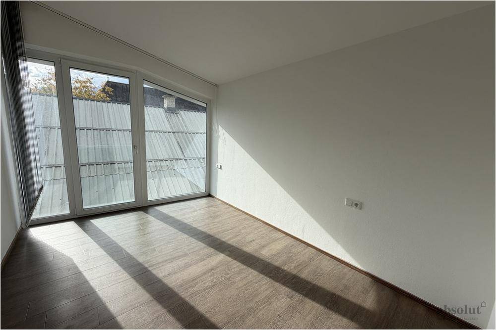 Helles Zimmer mit großen Fenstern, Laminatboden und viel Tageslicht.
