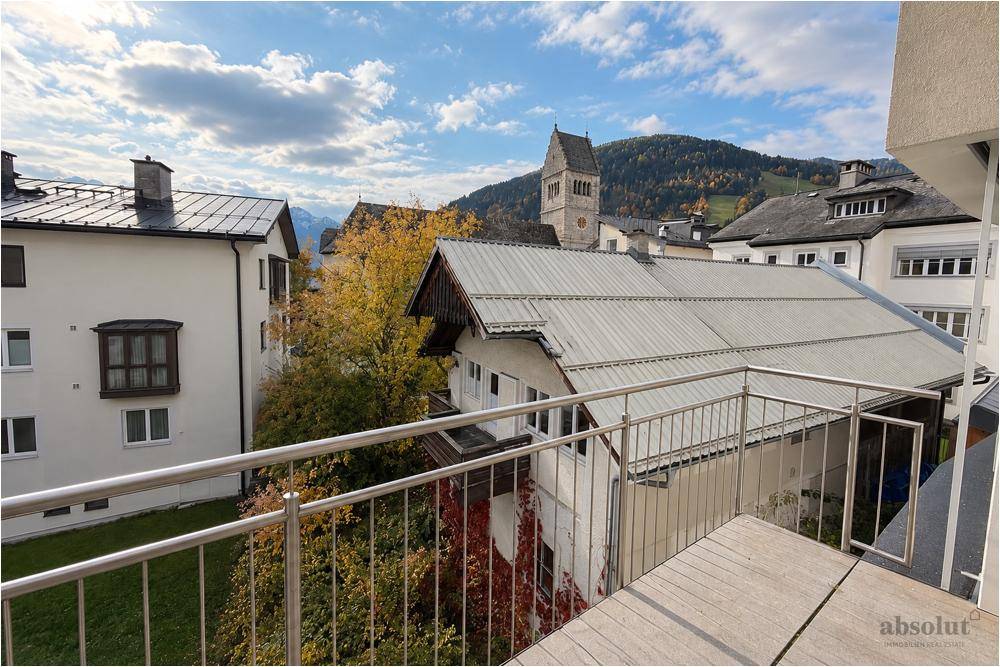 Balkon mit Blick auf die Dächer der Stadt und einen Kirchturm im Hintergrund.