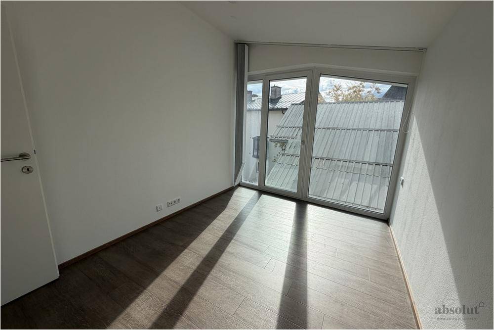 Sonniger Raum mit Laminatboden und großen Fenstern, die viel Licht hereinlassen.