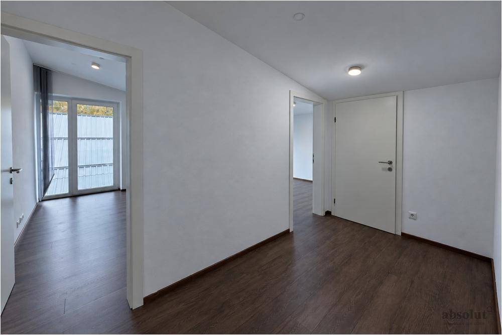 Heller Flur mit modernem Laminatboden, der zu verschiedenen Zimmern führt.
