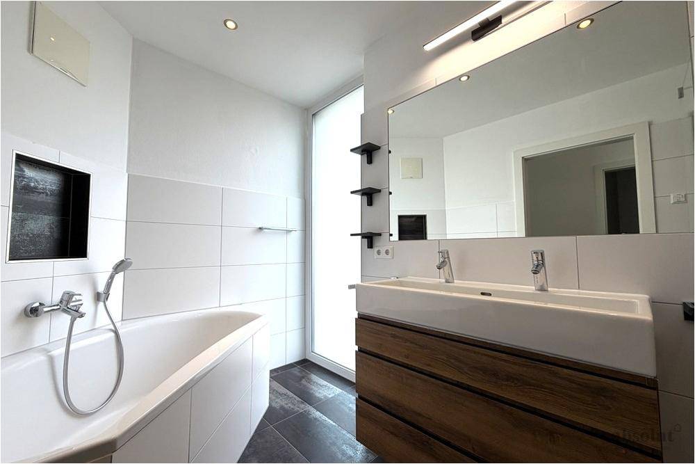 Modernes Badezimmer mit Doppelwaschbecken, Badewanne und großem Spiegel.