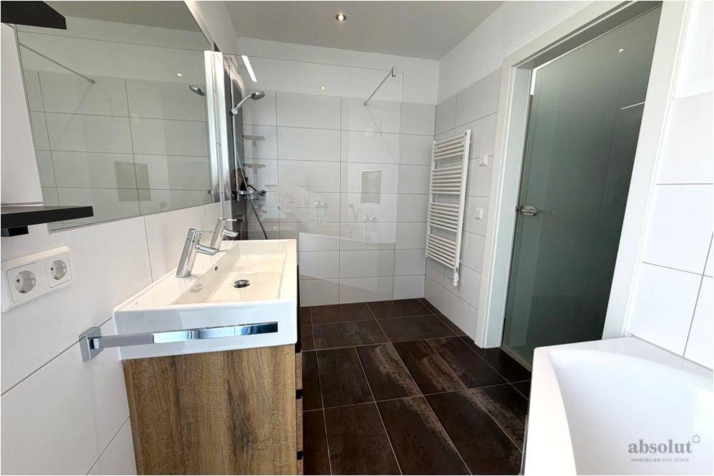 Helles Badezimmer mit Dusche, Badewanne und modernem Waschtisch.