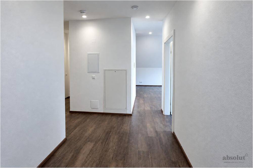 Langer, heller Flur mit Laminatboden und Zugang zu weiteren Räumen im Dachgeschoss.