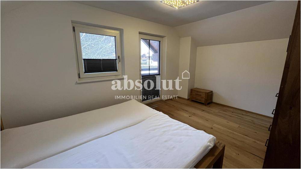 Helles Schlafzimmer mit Doppelbett, Holzboden und Zugang zum Balkon.