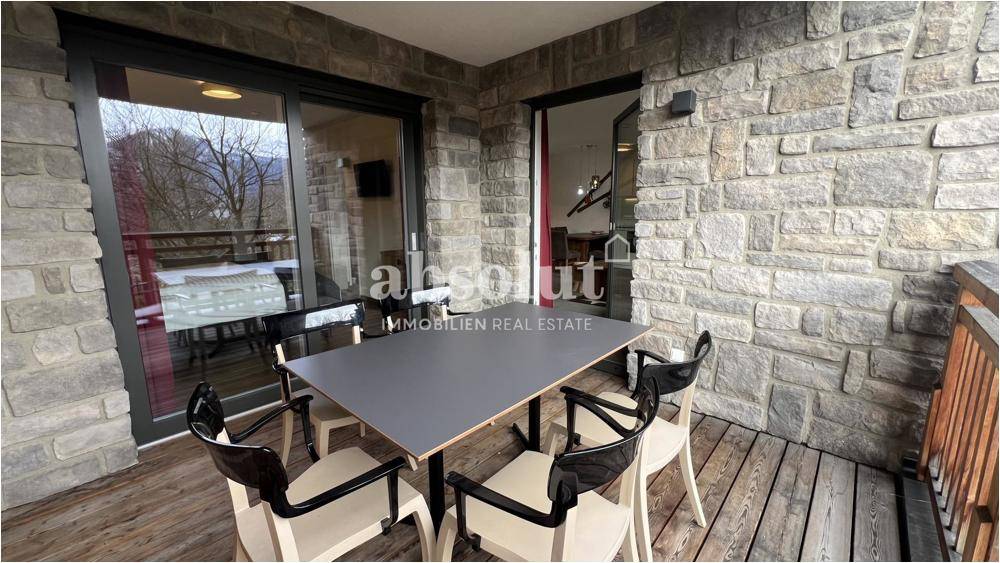 Gemütlicher Balkon mit Holzboden, Steinfassade und Sitzgelegenheiten im Freien.