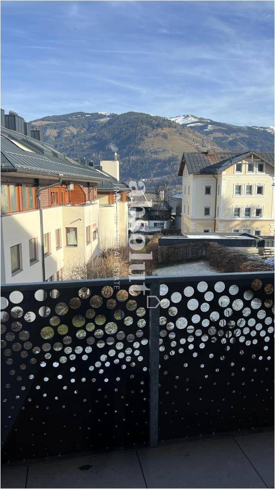 Panoramablick vom Balkon auf die umliegende Berglandschaft und benachbarte Gebäude.
