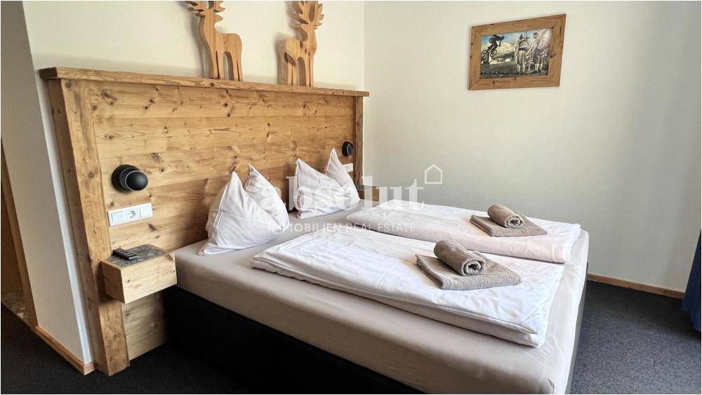 Schlafzimmer mit rustikalem Holz-Kopfteil, bequemen Betten und traditioneller Dekoration.