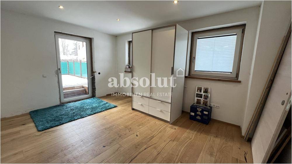 Schlafzimmer mit Holzboden, Kleiderschrank und Zugang zu einer Außenterrasse.