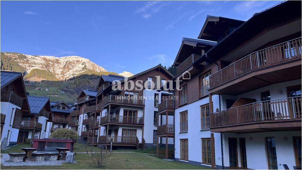 Moderne Chalet-Architektur mit Holzbalkonen und beeindruckendem Bergblick im Hintergrund.