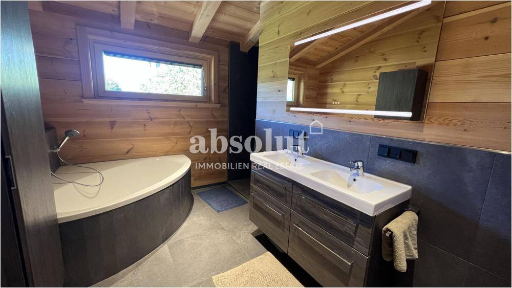 Geräumiges Badezimmer mit Doppelwaschbecken, Badewanne und Dachschräge im Holzdesign.