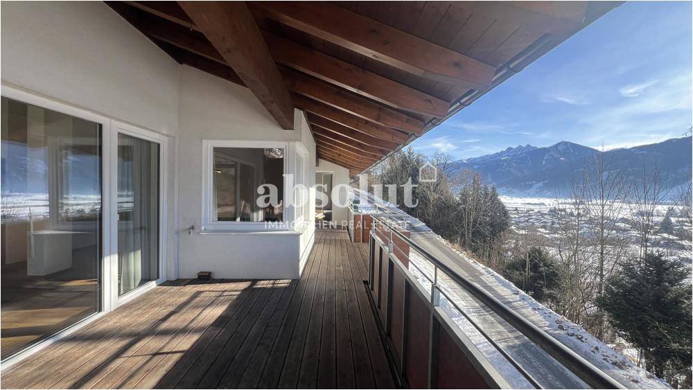 Breiter Holzbalkon mit Panoramablick auf die verschneite Landschaft und die Berge.