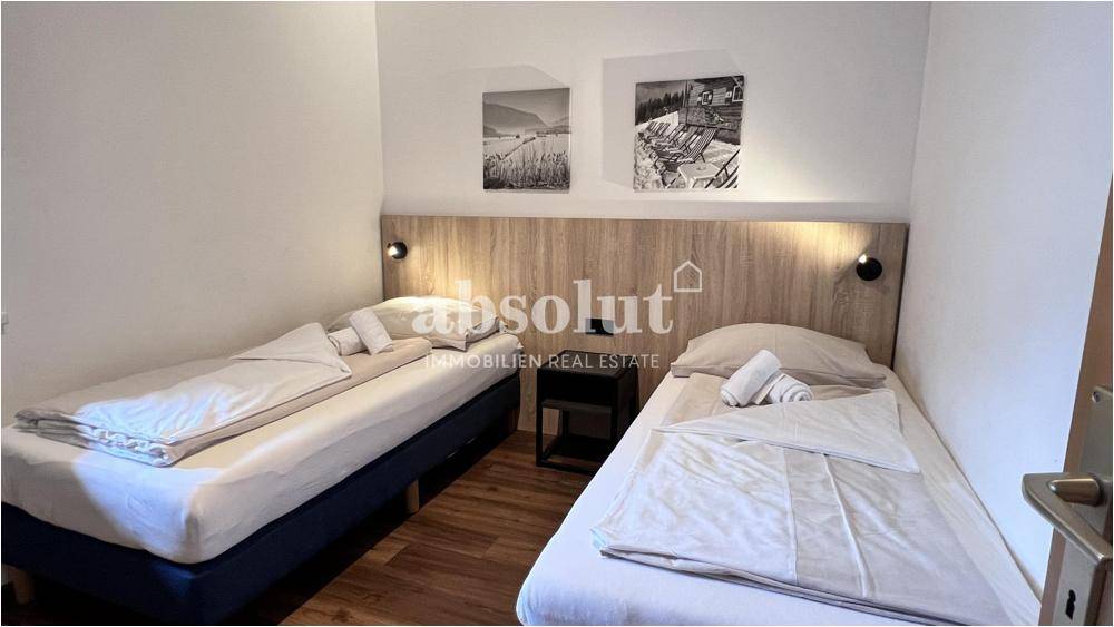 Schlafzimmer mit zwei Einzelbetten, Holzkopfteil und schlichtem, funktionalem Design.