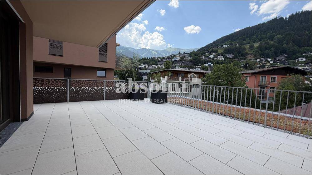 Geräumige Terrasse mit Fliesenboden und Panoramablick auf die Berge und das Tal.