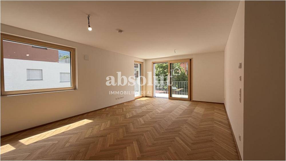 Helles Wohnzimmer mit Fischgrätparkett und Zugang zu einem französischen Balkon.