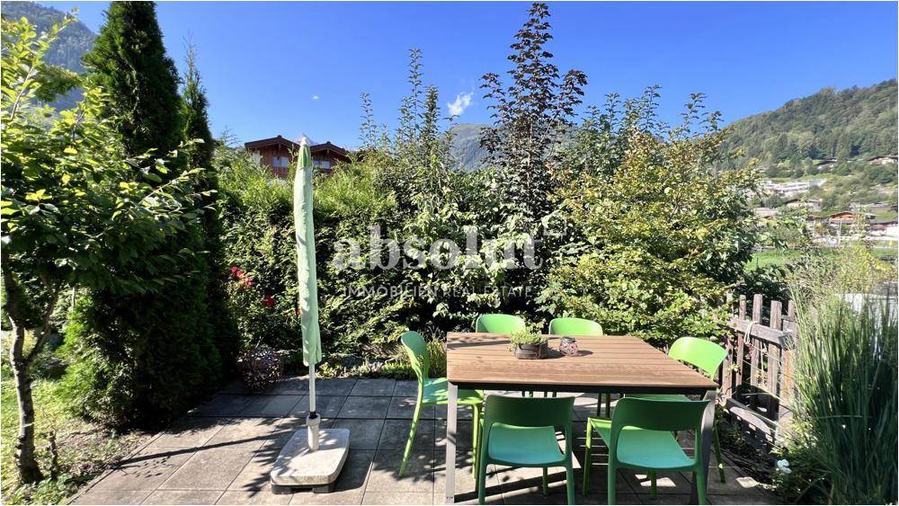 Gemütlicher Gartenbereich mit Sitzgelegenheiten, umgeben von Hecken und Bäumen.