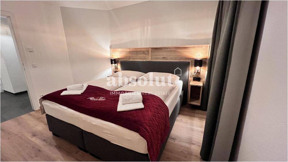 Gemütliches Schlafzimmer mit Doppelbett, Holzkopfteil und Nachttischen mit Beleuchtung für eine angenehme Atmosphäre.