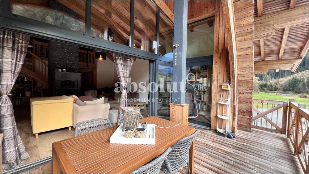 Geräumige Terrasse mit Holzboden und Blick auf den hellen Wohnbereich durch große Glasfronten.