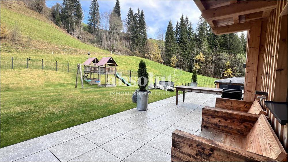 Gepflegter Garten mit Rasenfläche, Kinderspielplatz und angrenzender Terrasse.