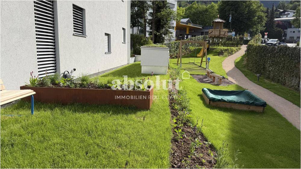 Gemeinschaftlicher Gartenbereich mit Spielplatz, Sandkasten und Schaukel für Kinder.