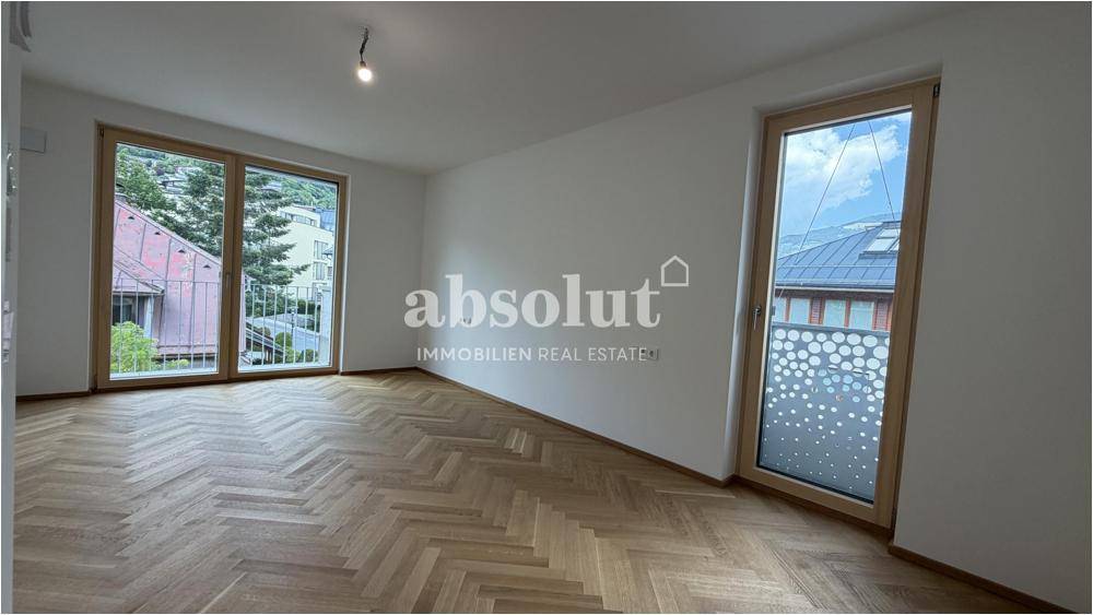 Helles Schlafzimmer mit Fischgrätparkett und Zugang zu einem französischen Balkon.