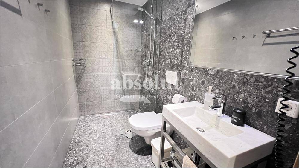 Modernes Badezimmer mit begehbarer Dusche, Wand-WC und stilvollen Fliesen.