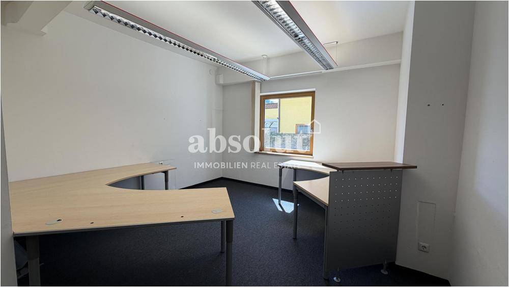 Büroraum mit mehreren Arbeitsplätzen, Teppichboden und effizienter Deckenbeleuchtung.
