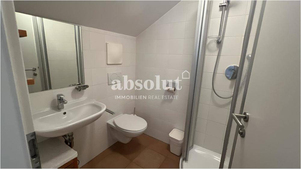 Modernes Badezimmer mit Dusche, wandhängendem WC und weißen Fliesen.