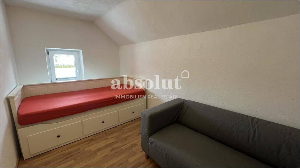 Kinder- oder Gästezimmer mit Bett, Sofa und Laminatboden im Dachgeschoss.