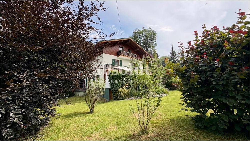 Weitläufiger Garten mit üppiger Bepflanzung und dem charmanten Wohnhaus im Hintergrund.